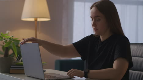 Die-Junge-Frau-Beendet-Ihre-Arbeit-Mit-Dem-Laptop,-Schließt-Die-Abdeckung-Und-Schaltet-Das-Licht-Im-Zimmer-Aus.-Sie-Arbeitet-Von-Zu-Hause-Aus-Und-Entspannt-Sich-Nach-Der-Arbeit